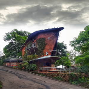 A brick house located beside a road, showcasing the architectural style of the Houses of Goa Museum in Goa.