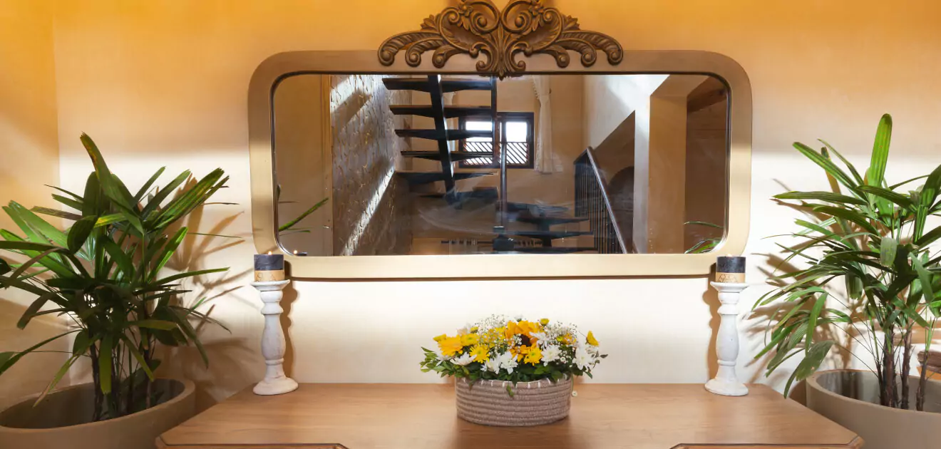 A mirror on a table with a basket of flowers
